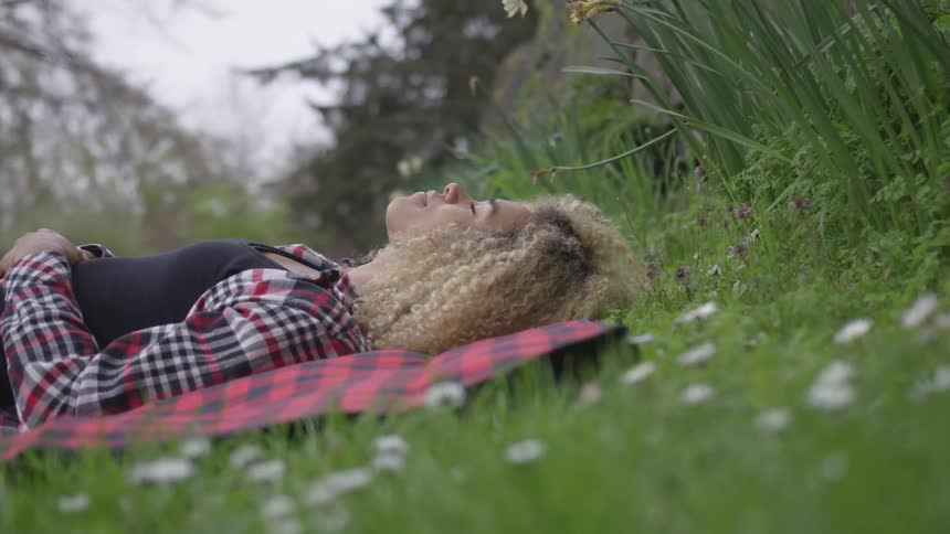 A woman laying on a blanket in a woodland