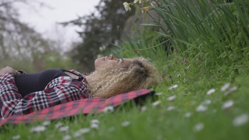 A woman laying on a blanket in the grass