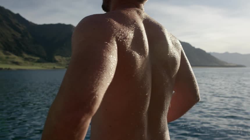 A man shakes off water from a river on a sunny day