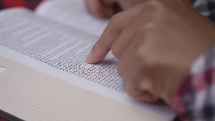 A person points at the page of a bible while reading