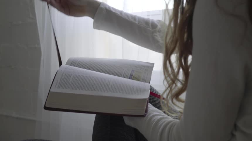 Woman reading bible places bookmark