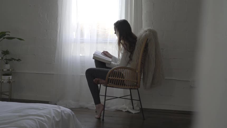 Woman sits in bedroom reading