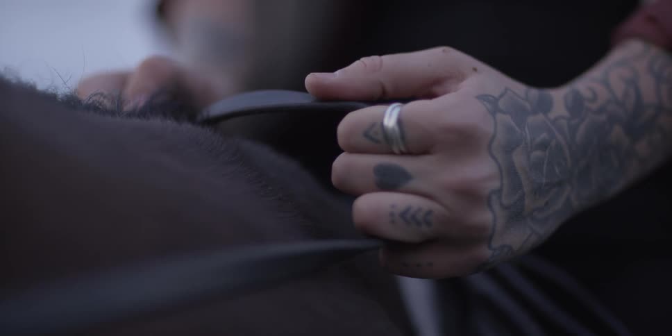 A man with tattoos is riding a horse