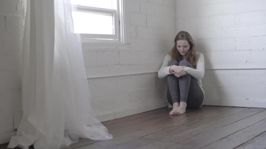 Girl sitting in the corner of a room