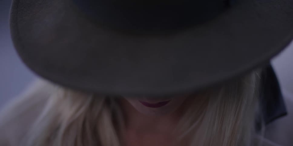 A woman in a black hat bows her head