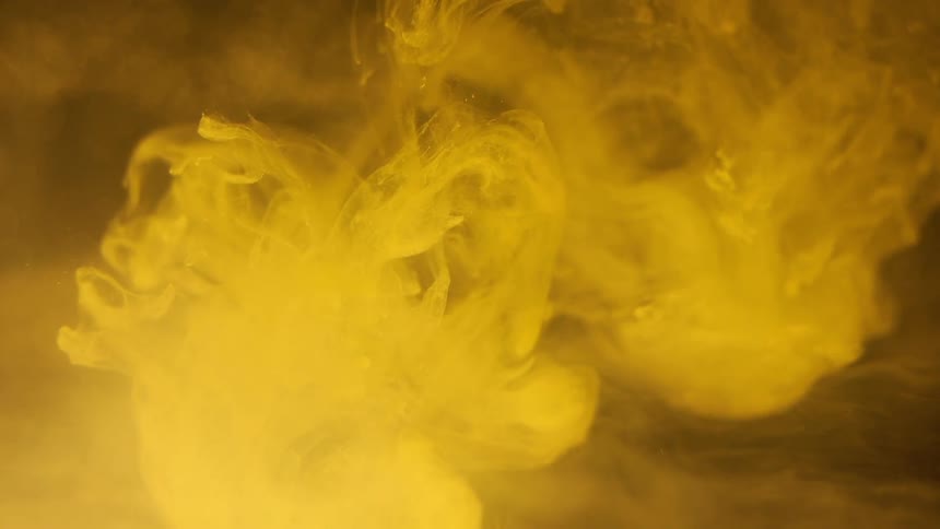 Yellow colored substance swirling through another liquid