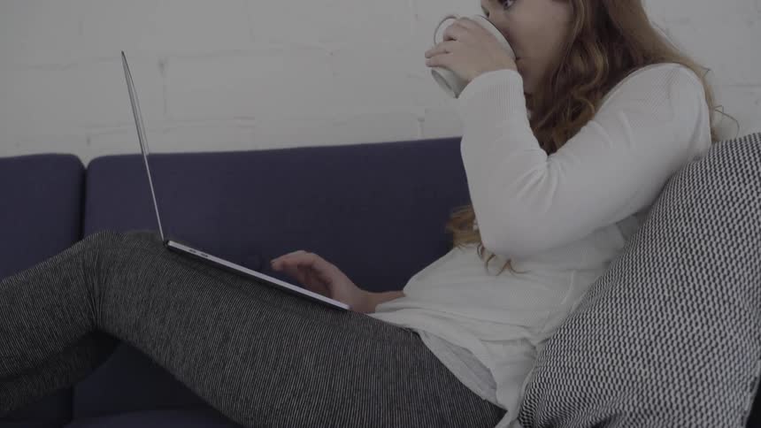 A woman takes a sip of a drink and places it on the table