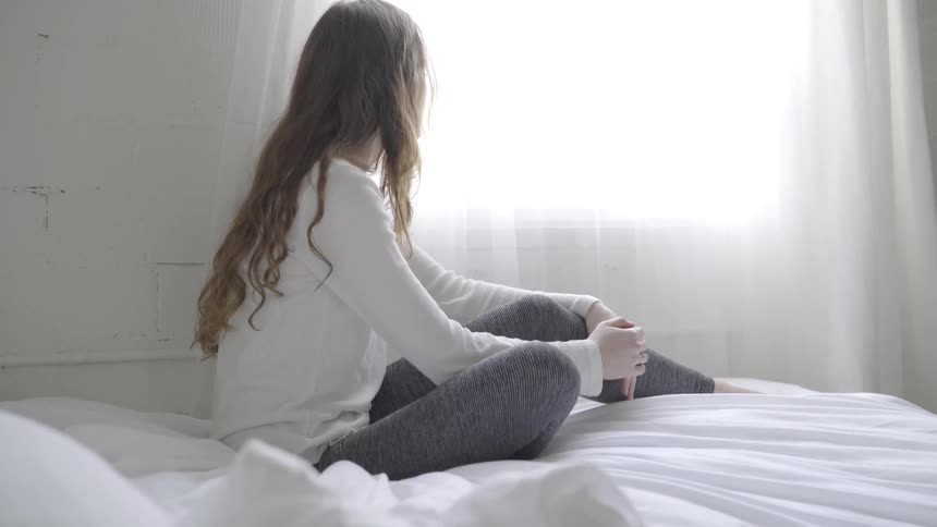A young woman sits on a bed