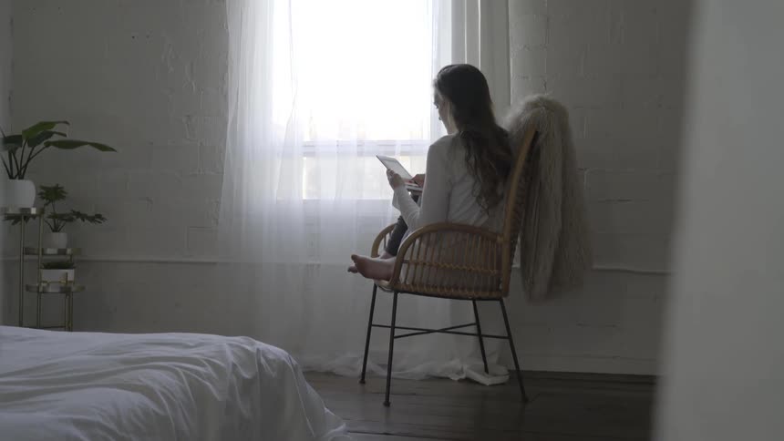A woman sitting by a window reading