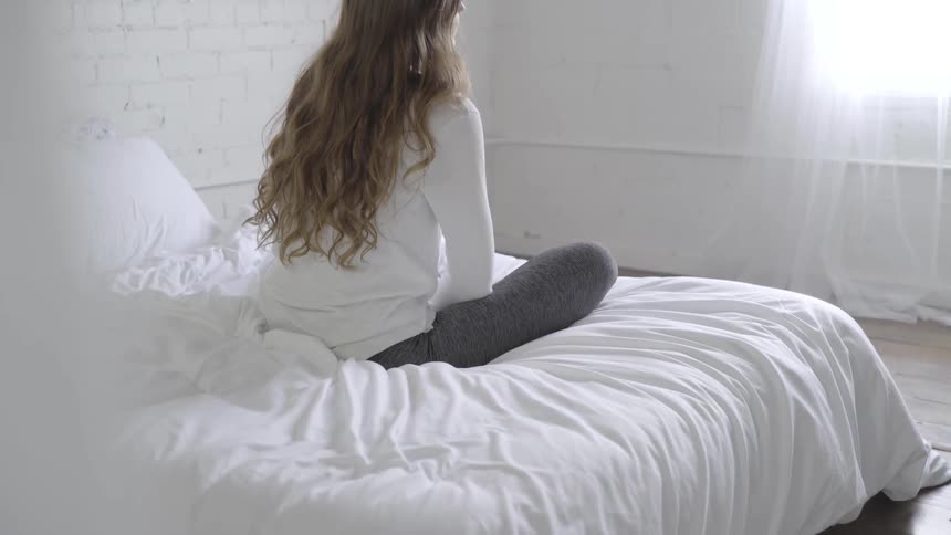 Woman sits on bed