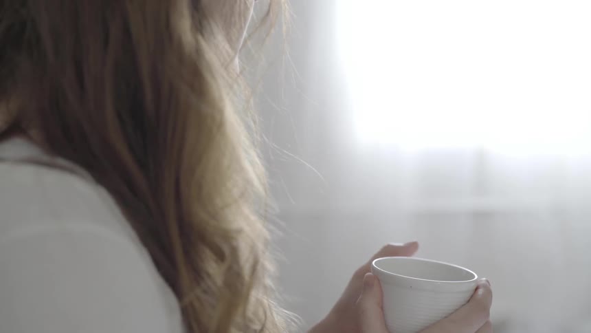 A woman holds a mug in her hand