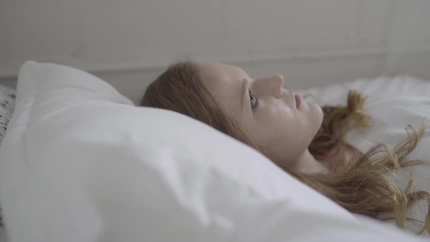 A woman flops down on to a bed