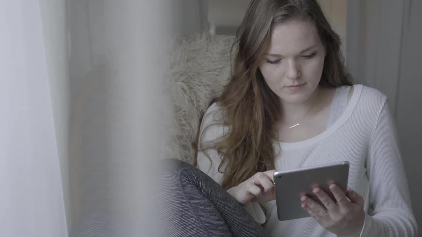 A woman sitting in a chair using a tablet
