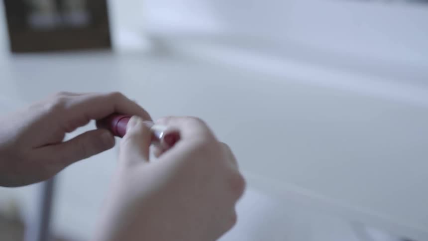 A woman picks up a tube of makeup
