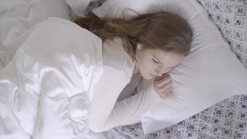 Woman lying on her bed with open eyes