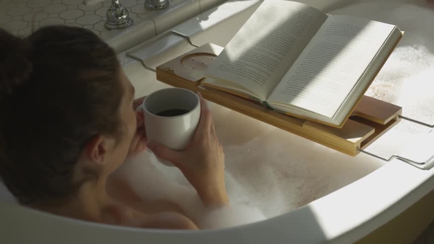 A woman is drinking coffee in a bathtub