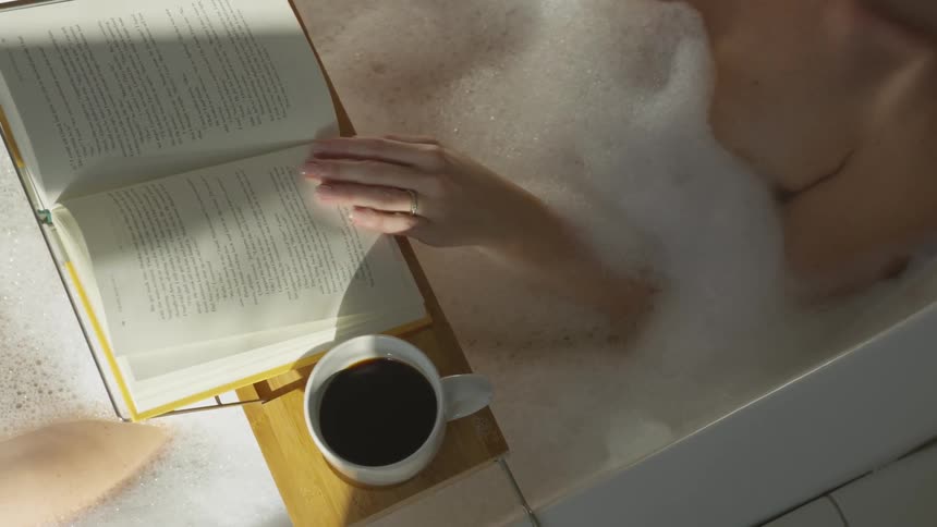 A woman in a bath reading from a book on a book stand