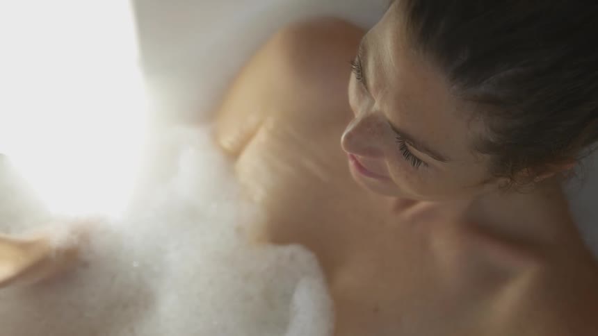 A woman lays in a bubble bath