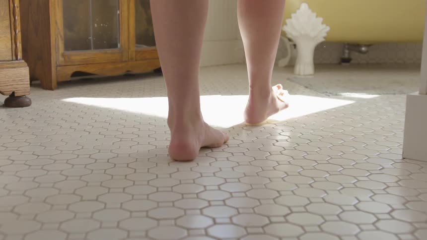 A person walks into a sunlit bathroom