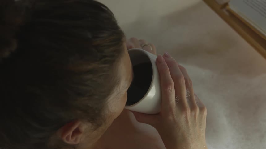 A white woman drinks a cup of coffee