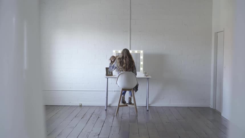 A woman is sitting down and looking at herself in the mirror