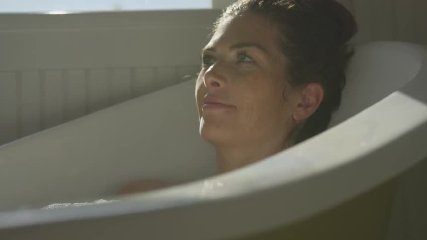 A woman sits in a bathtub relaxing