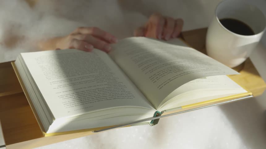 Person reads book on lap tray