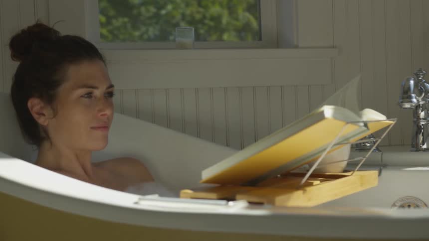 Girl lying in a bathtub reading