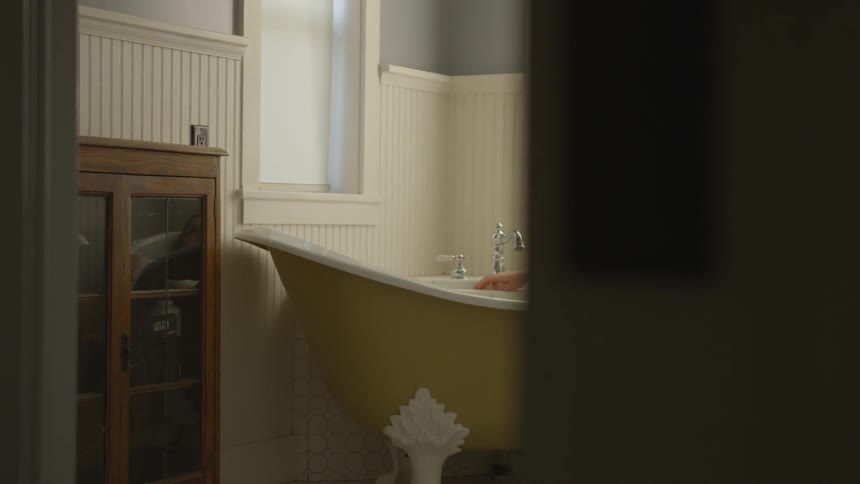 Female relaxing while soaking in a yellow antique bathtub