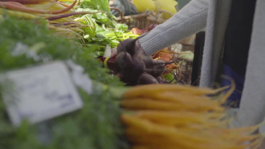 A woman picking up some beets at a store