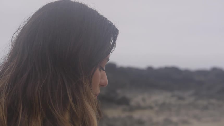 A woman standing at the edge of a mountain looking down