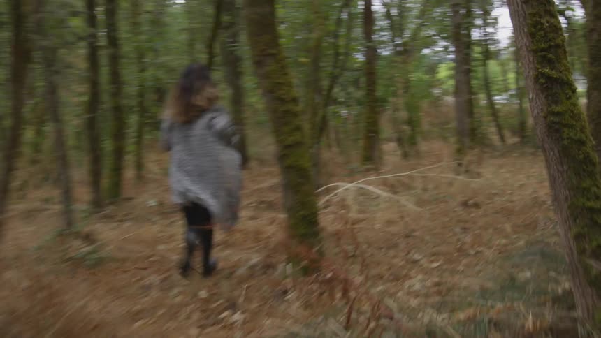 A young woman runs through a forest