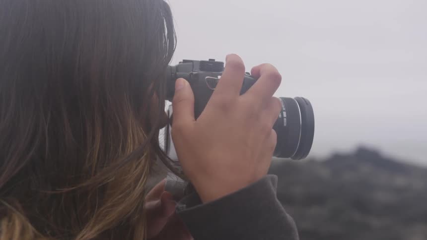 A woman looks through the viewfinder of her camera and takes photos