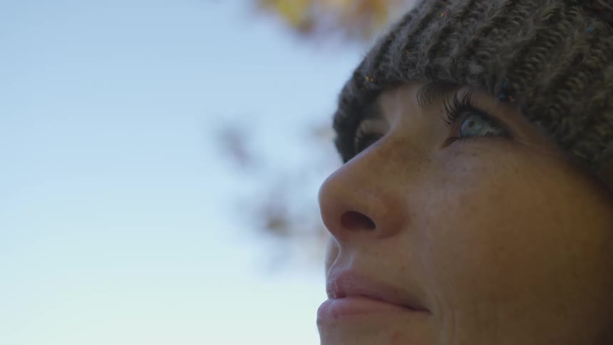 A woman wearing a winter hat looks up at the sky
