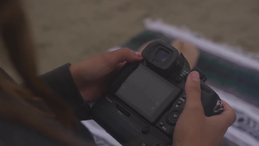 A woman looks at the screen on a digital camera