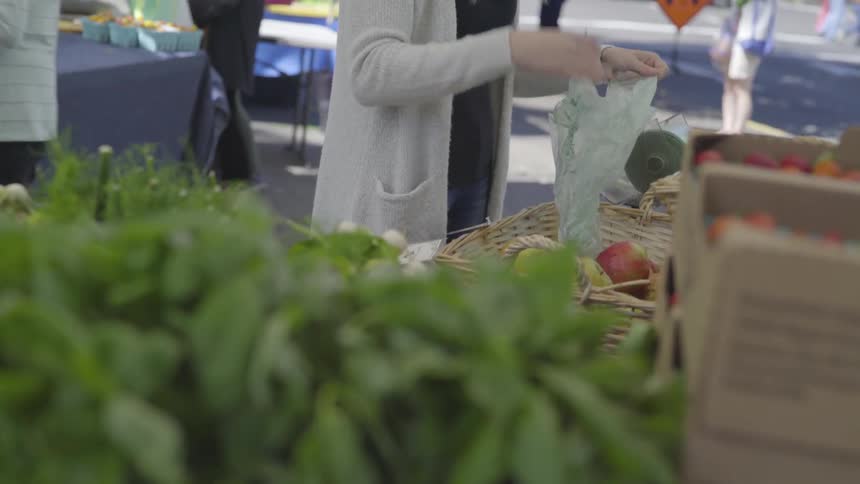 A woman is picking produce at a market