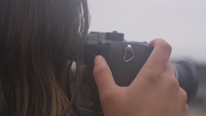 A dark haired woman uses a camera to take a picture