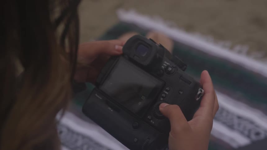 A young woman looks down at a camera