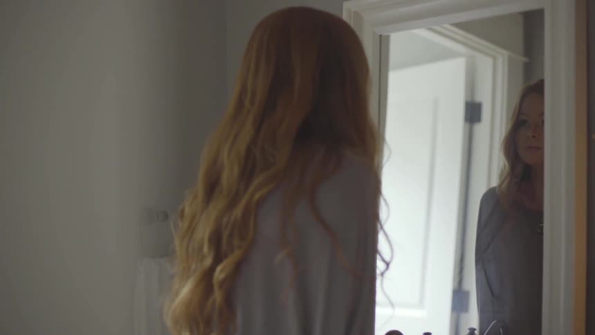 A young woman looks in a mirror