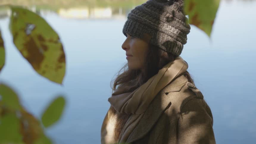 Woman wearing winter clothing stands outdoors staring intently