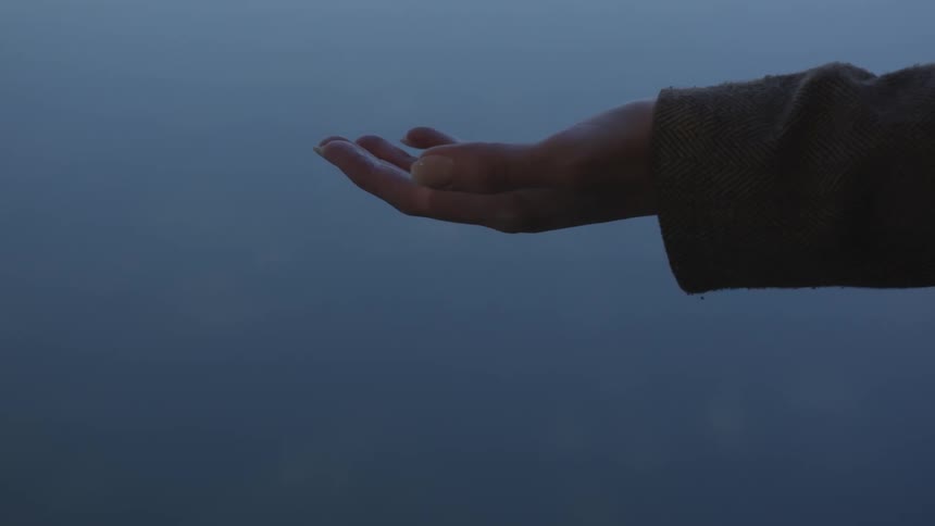 A white woman stretches out her arm with her palm facing upwards