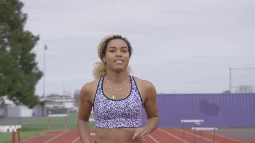 A woman bounces and jumps up and down on a track as she stretches and warms up