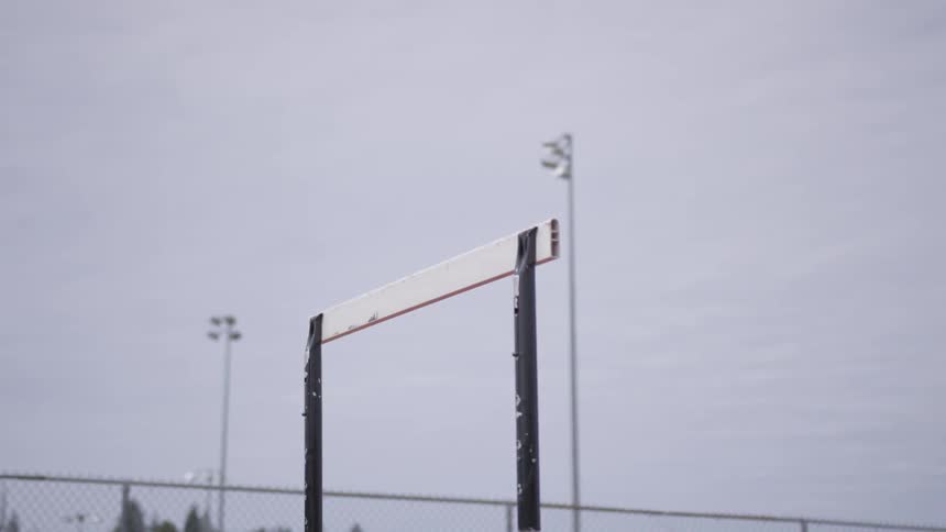 A woman leaps over a hurdle while running on a track
