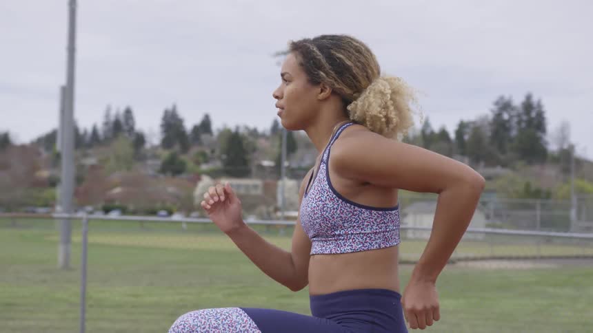 Black woman wearing fitness clothes warming up in a public park