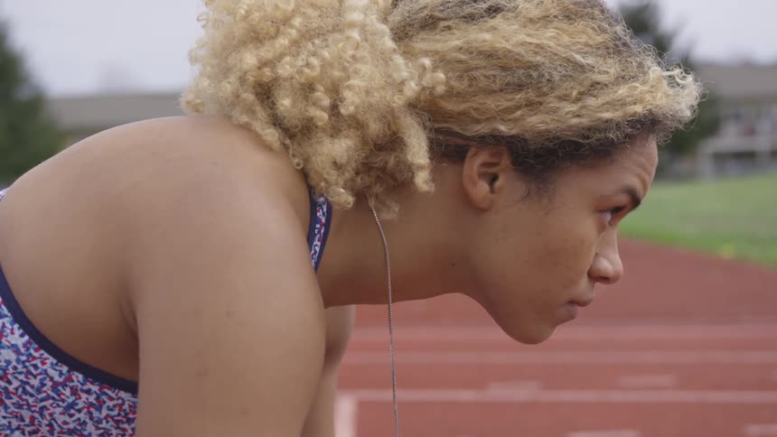 A woman gets in position to start racing on a track