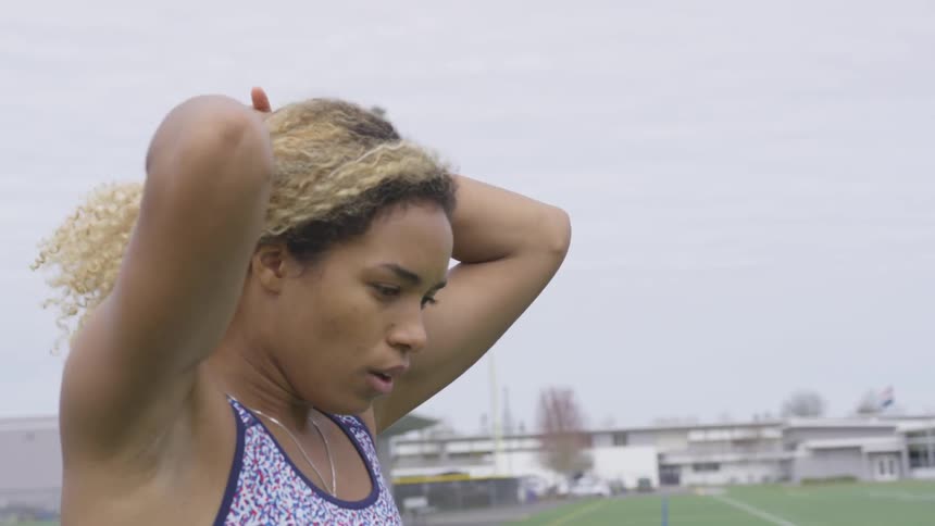 A woman stretches on the football field