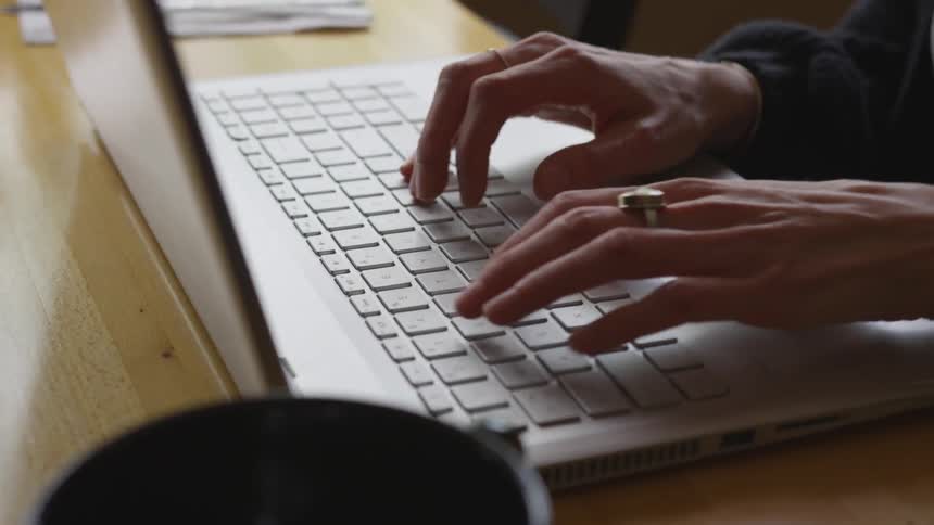 A woman types on a laptop
