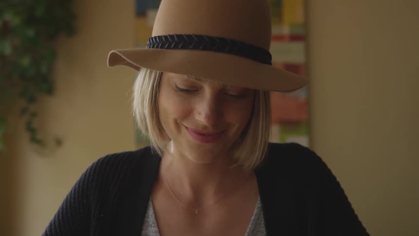 A young woman is smiling while looking at her cell phone