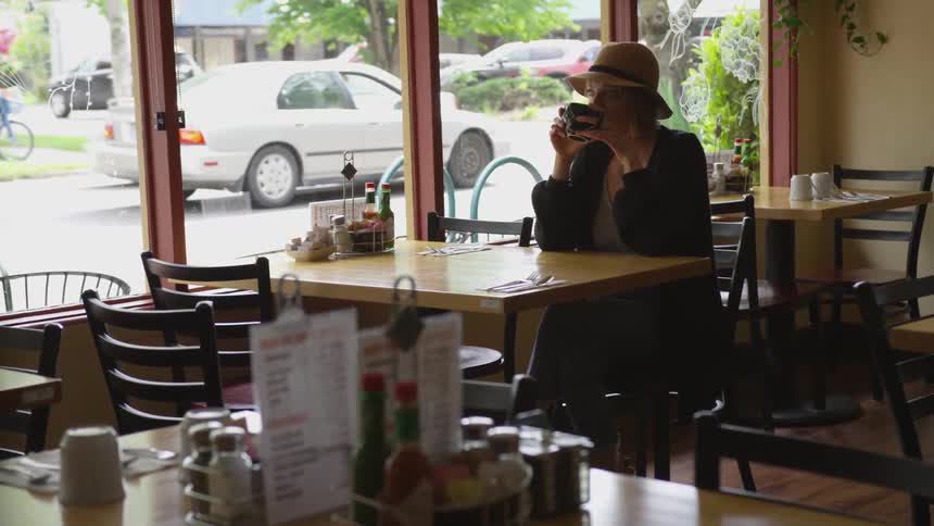 A woman sips from a cup in a restaurant
