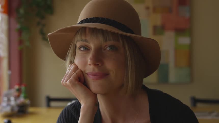 A woman smiles while turning her head to the camera